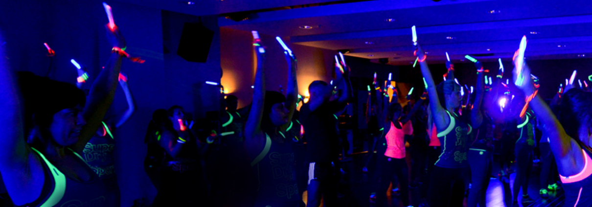 People in a darkened room doing Clubbercise with glow sticks