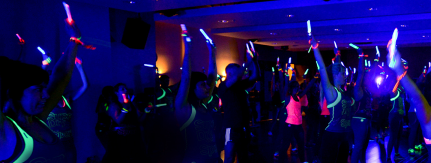 People in a darkened room doing Clubbercise with glow sticks