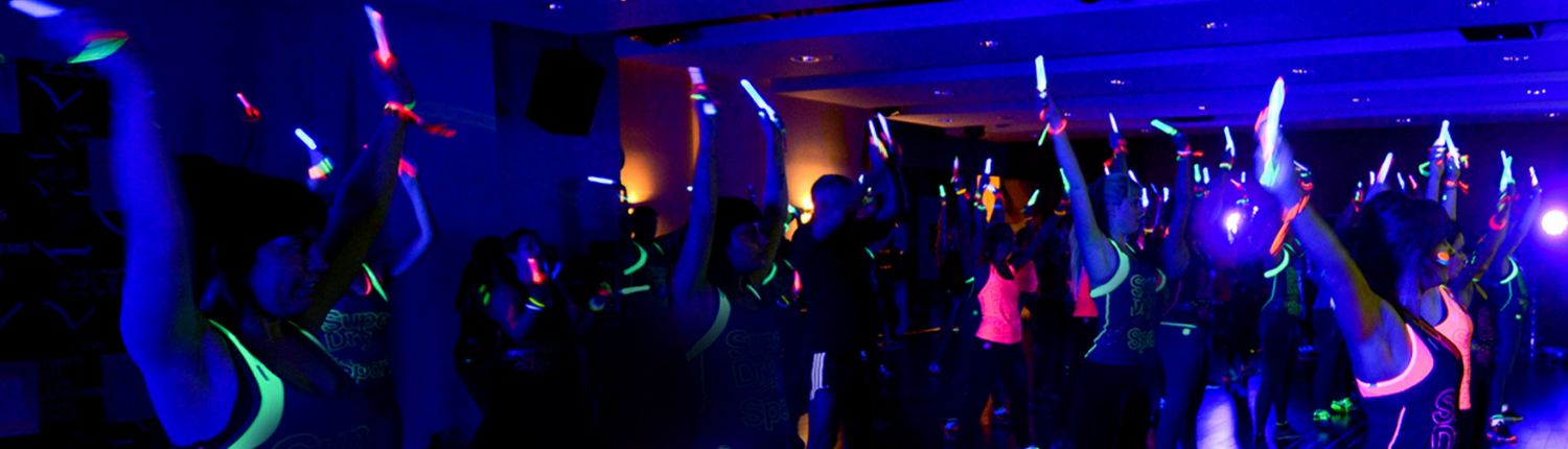People in a darkened room doing Clubbercise with glow sticks