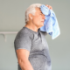 A white older man holding a sweat towel to his head