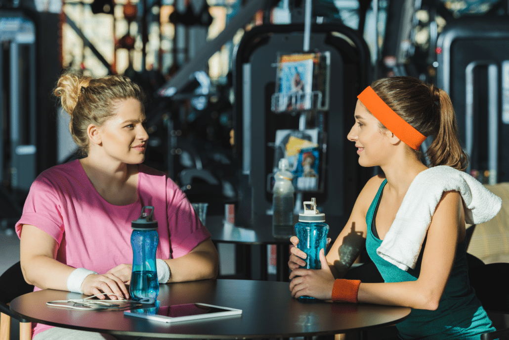 Exercise instructor talking to member at gym