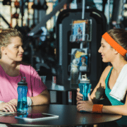 Exercise instructor talking to member at gym