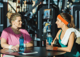 Exercise instructor talking to member at gym