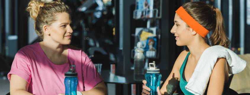 Exercise instructor talking to member at gym