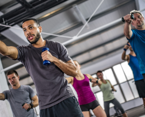 Men and women exercising with dumbbells in gym.