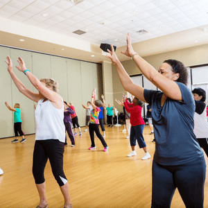 Group of mixed age and mixed ethnicity individuals dancing in a community centre or gym studio